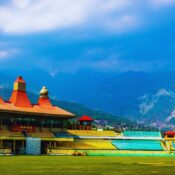 Stunning aerial view of the Himachal Pradesh Cricket Association Stadium, Dharamshala with the majestic Dhauladhar mountains in the background — a world-renowned cricket venue surrounded by Himalayan beauty.
