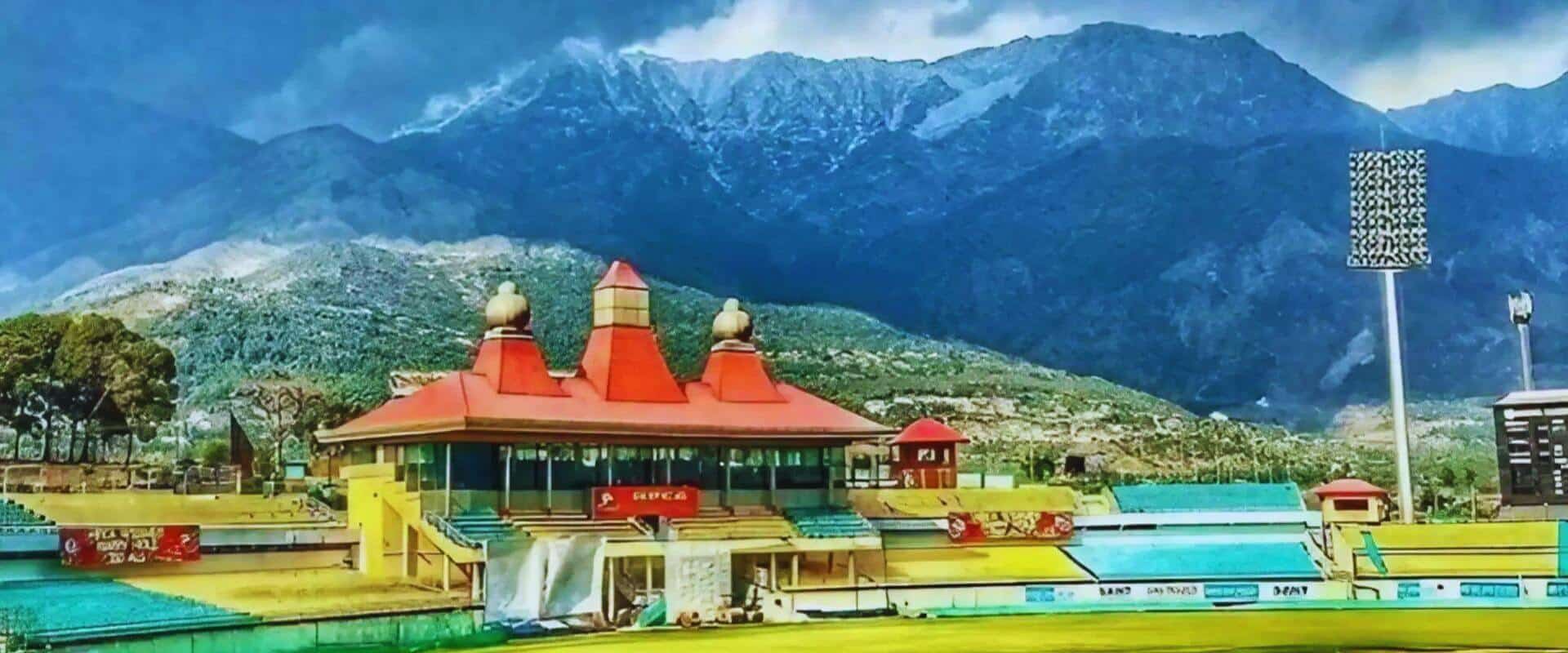 Stunning aerial view of the Himachal Pradesh Cricket Association Stadium, Dharamshala with the majestic Dhauladhar mountains in the background — a world-renowned cricket venue surrounded by Himalayan beauty.
